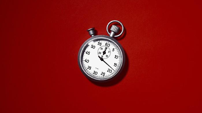 A metal and white face stopwatch on a red background.