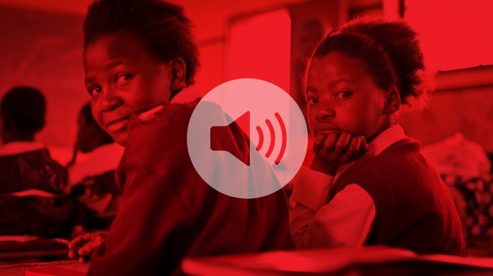 Two young black girls in a classroom with a red overlay and speaker icon