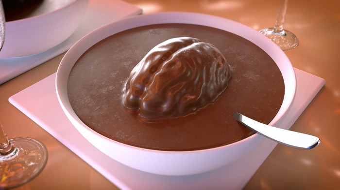 A white bowl full of brown liquid with the shape of a brain floating in it sits on table