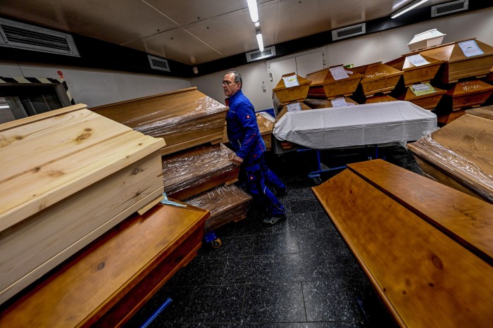A member of staff pushes a stack of coffins in a storage room full of coffins in a crematorium in Germany