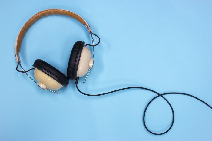 Headphones on a blue background with its cord going off to the side.