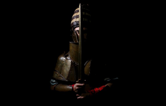 Artistic photo showing someone holding a sword and a replica of the Dendra armor used in the study.