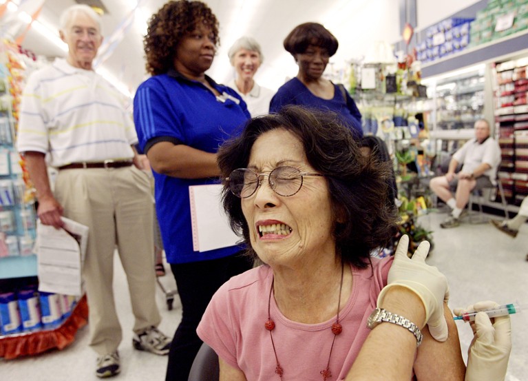 Woman reacting to getting a flu shot in a drug store