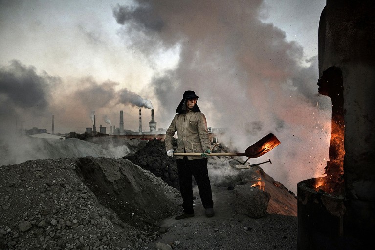 A worker shovels coal in a coal-fired factory in China