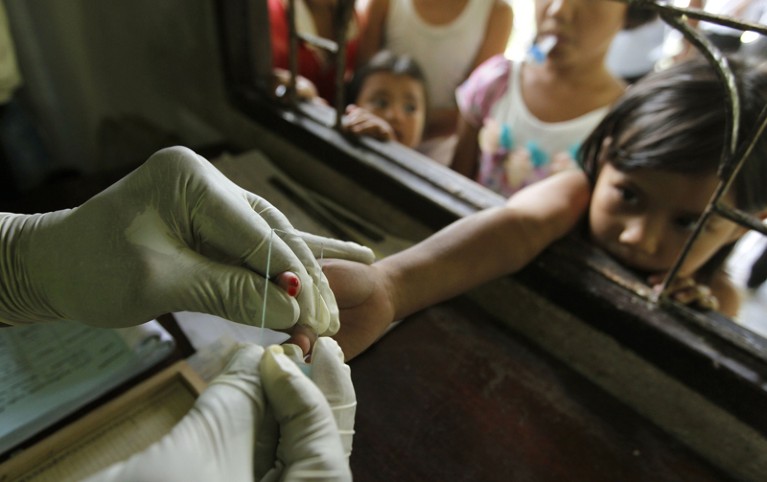 A Thai health official takes a blood sample from a child's finger for a malaria test