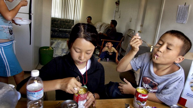 Hmong children eat soup from cans in Sacramento, California.