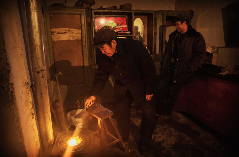 Chinese farmer stokes a coal stove
