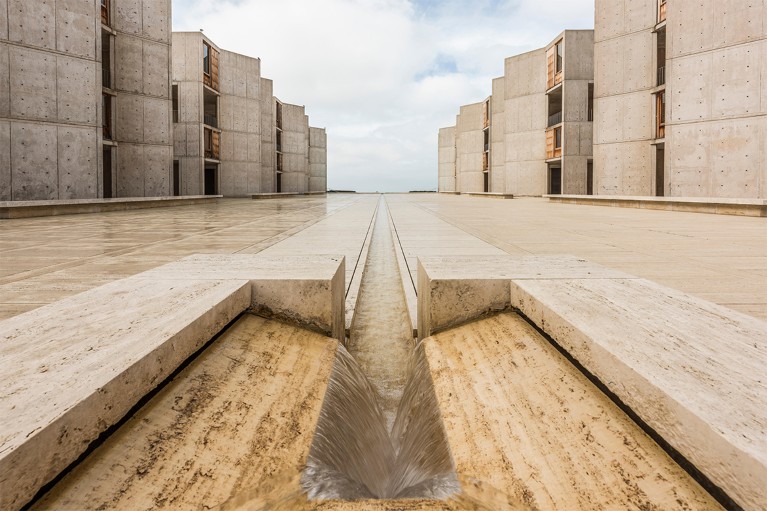 Open stone courtyard at the Salk Institute, with a perspective view of the water feature, and office buildings to either side