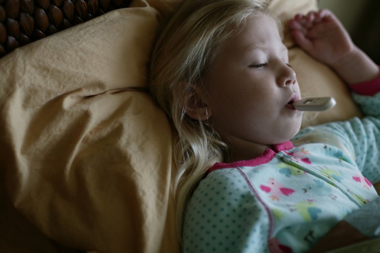 Girl sick in bed with thermometer