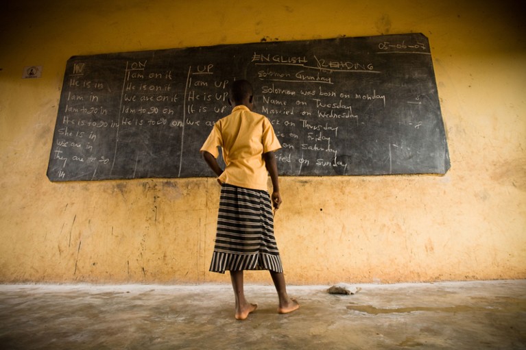 Girl standing at a blackboard at a primary school in Ghana
