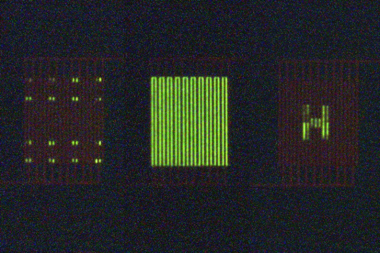 Three organic light-emitting transistors displaying different patterns of green light