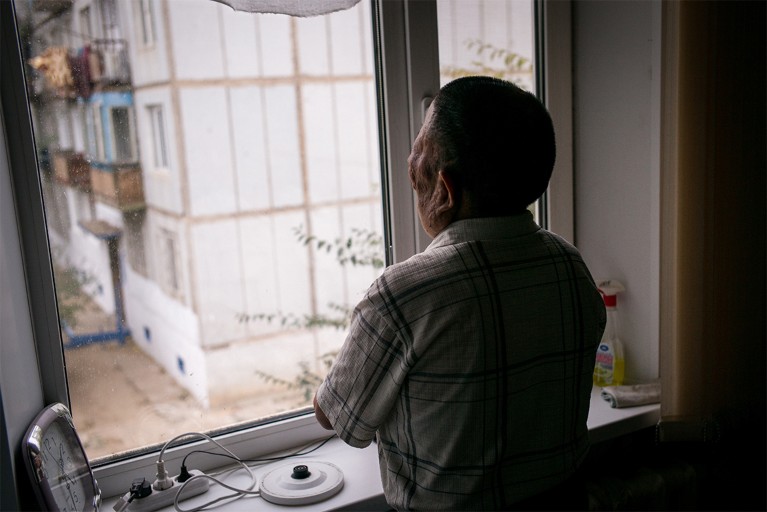 Berik Syzdykov looks out of the kitchen window in his home in Semey, Kazakhstan.