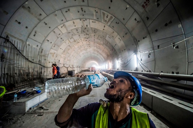 A construction worker drinks from a bottle of water at the site of a new road tunnel