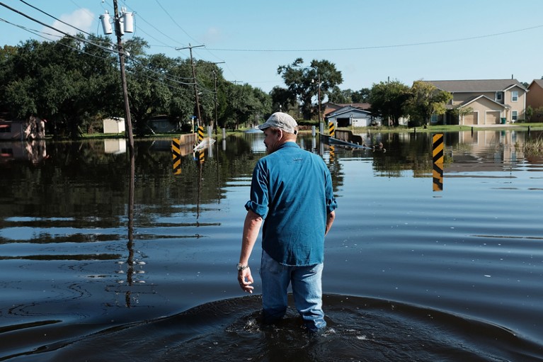 A man walks through knee-high flood waters in a Texas neighbourhood affected by Hurricane Harvey