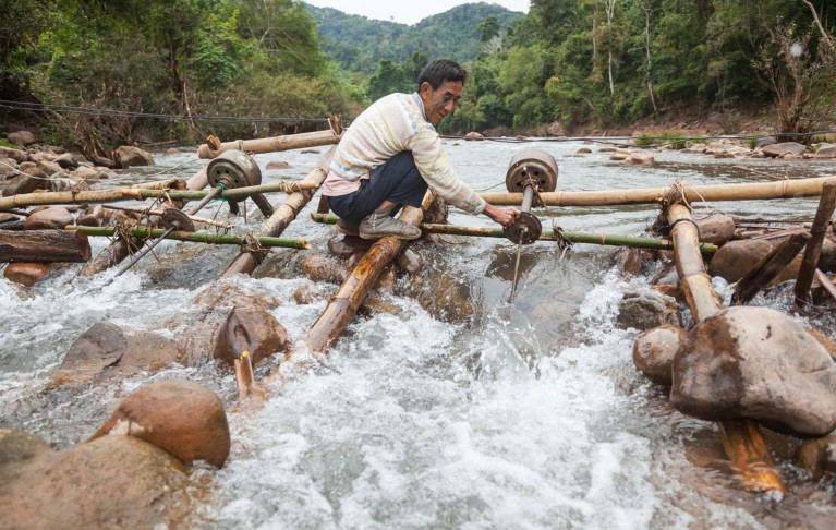 A man adjusts the propeller on a micro hydro turbine in the flow of the Nam Ou River at Ban Sop Kha, Laos.