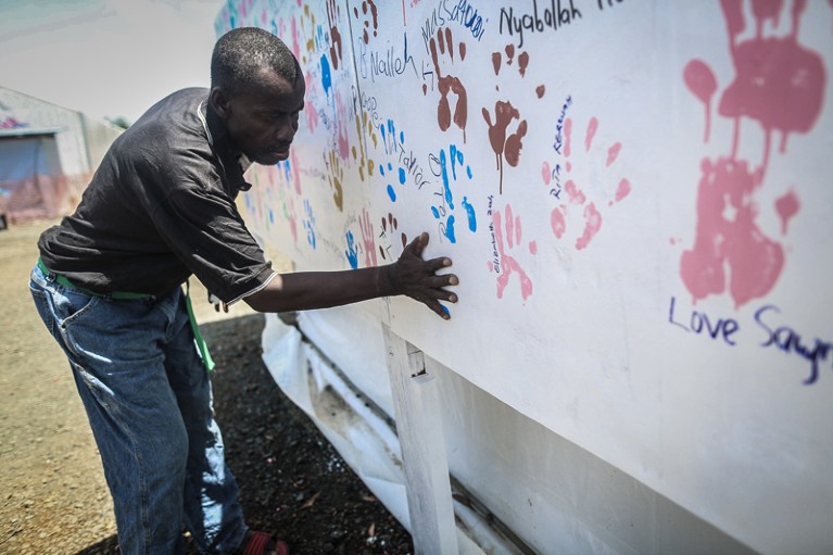 An Ebola survivor makes a handprint on a wall after being discharged from hospital, Liberia