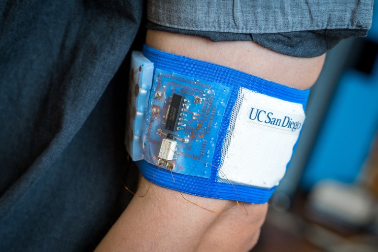 Person wearing a prototype cooling and heating patch embedded in a mesh armband.
