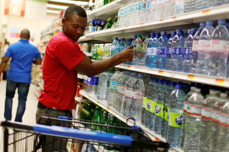 A supermarket employee puts water bottles on a shopping cart