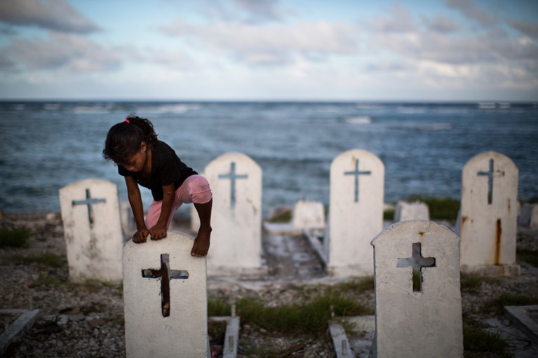 A girl climbs tombstones at a Jenrok cemetery, which has been partly washed away, on Majuro, Marshall Islands