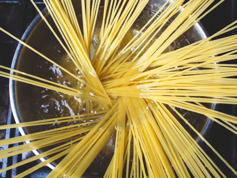 Spaghetti pasta is cooked in pan in boiling water.