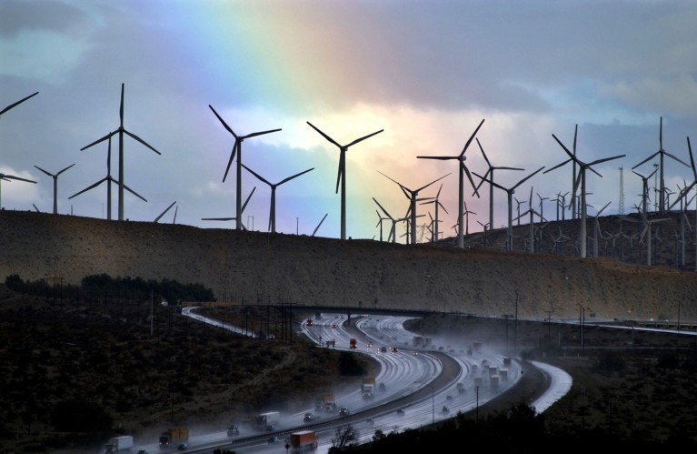 A rainbow forms behind wind-farm windmills near rain-soaked Interstate 10, Palm Springs, California