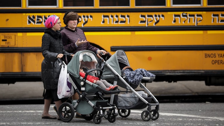 Women pushing strollers walk past the Yeshiva Kehilath Yakov School in the South Williamsburg neighborhood.