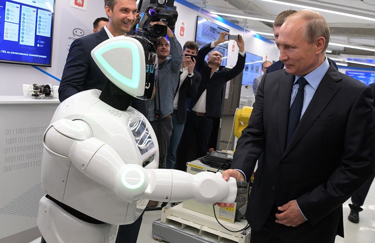 Vladimir Putin shakes hands with a robot at an exhibition by Russian businesses