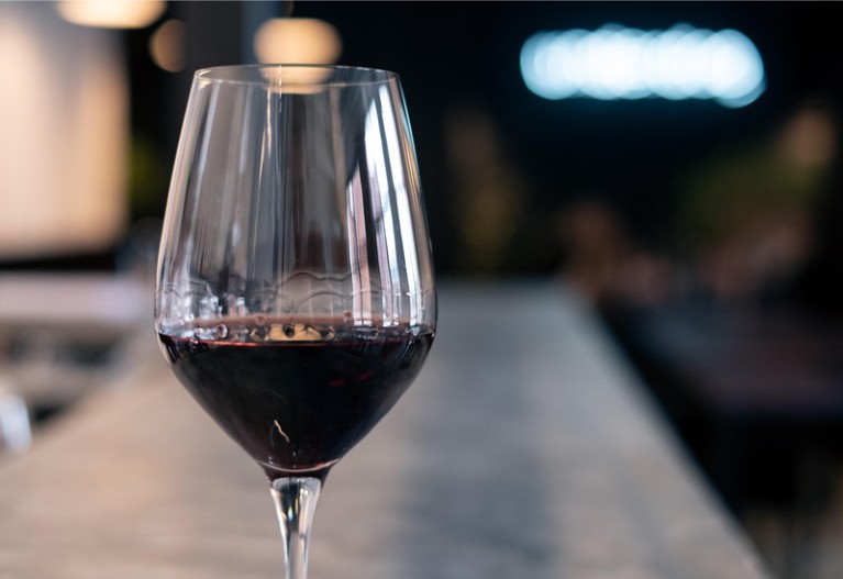 Close-up of a glass of red wine on a bar counter.