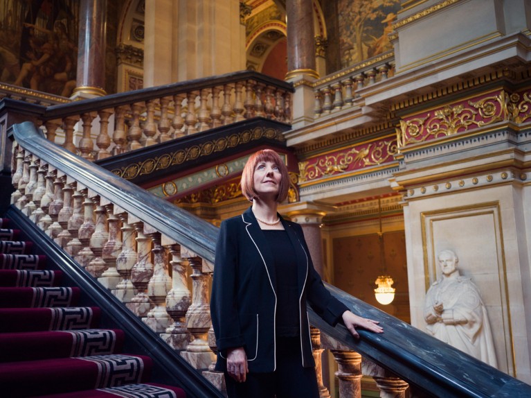 Carole Mundell poses for a portrait on an ornate staircase at the UK Foreign Office building