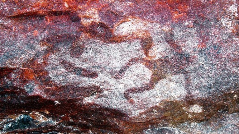 Designs on dark, reddish rock surrounded by white pigment.