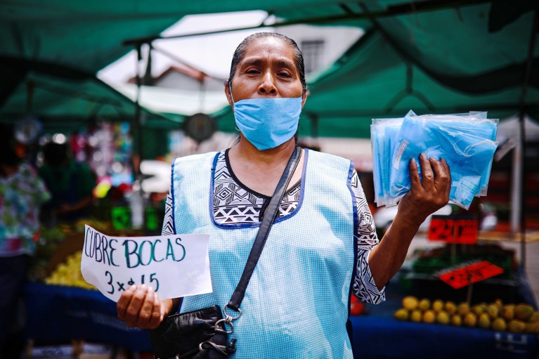 A woman wearing a face mask and apron sells face masks at a market in Mexico city