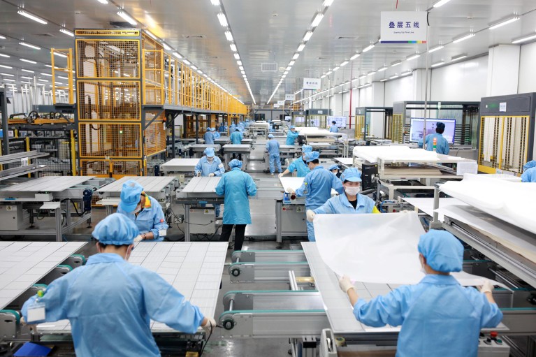 Employees work on photovoltaic solar panels at a factory in China