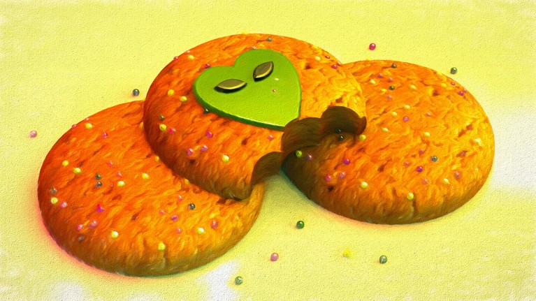A pile of 3 cookies – the top one has a picture of an alien on it and a bite taken out of it