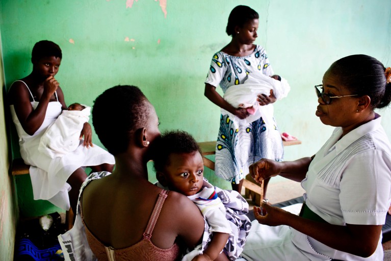 Women holding babies talk to a nurse about contraception in a health clinic in Ghana