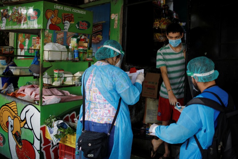 Healthcare workers wearing protective personal equipment examine a resident at his door