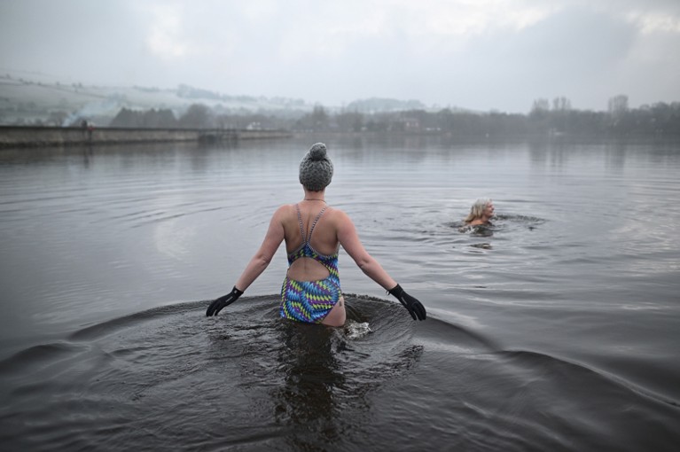 Individuals swimming in cold water outside.