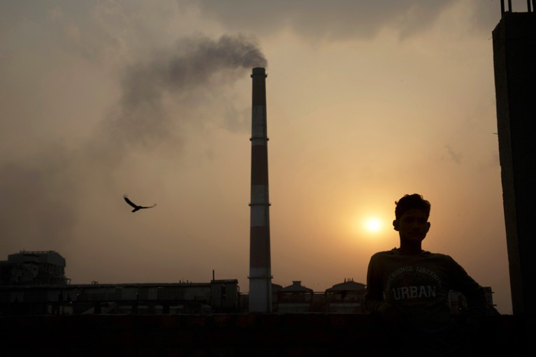 Emissions billow from smokestacks at a coal-fired power plant as the sun sets, India.