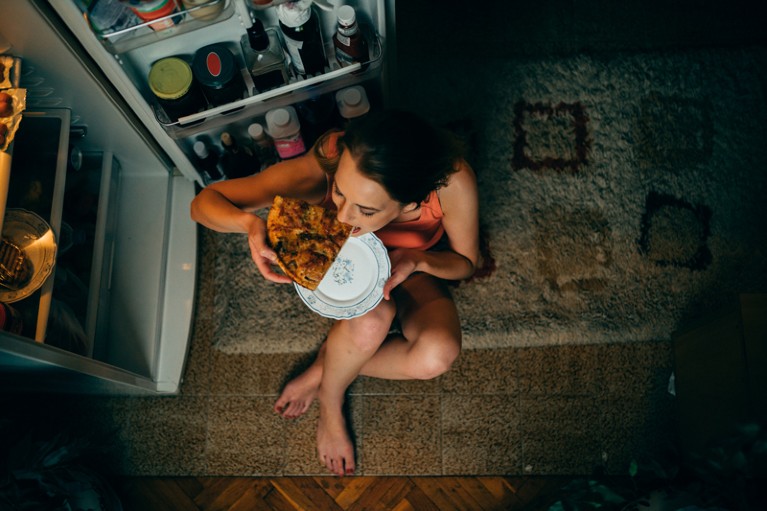 Woman eating in front of the refrigerator at night