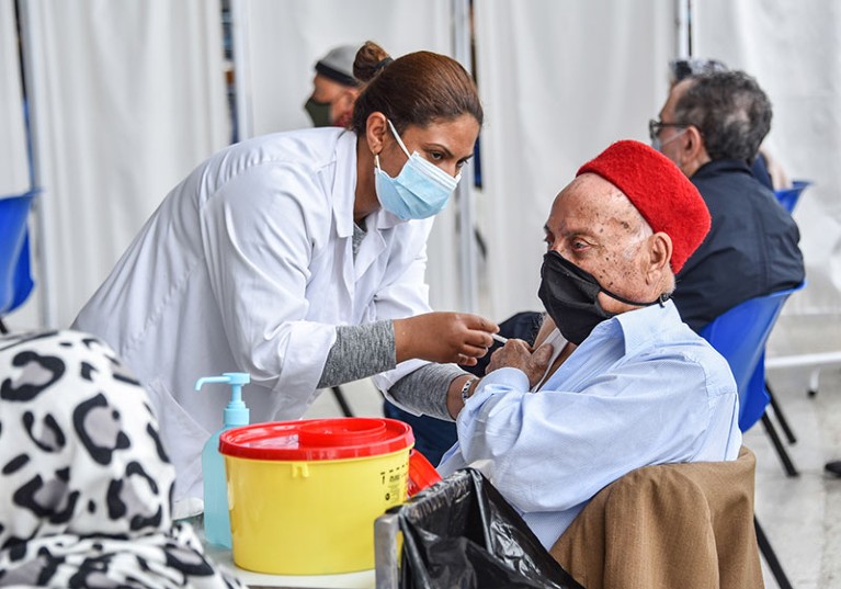 An elderly man receives a dose of the Pfizer-BioNTech COVID-19 vaccine at El-Menzah sports hall in Tunisia's capital.