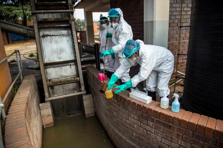 Three workers in PPE collect water samples from a South African water treatment facility, to be tested for traces o SARS-CoV-2
