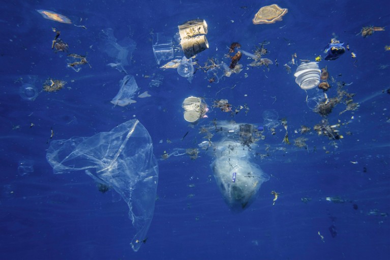 Plastic and other debris floats underwater in blue water