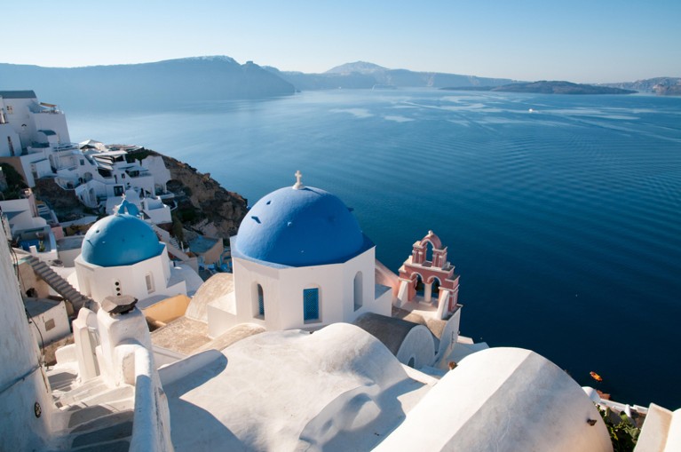 View over white buildings and blue painted church domes to the submerged Santorini caldera