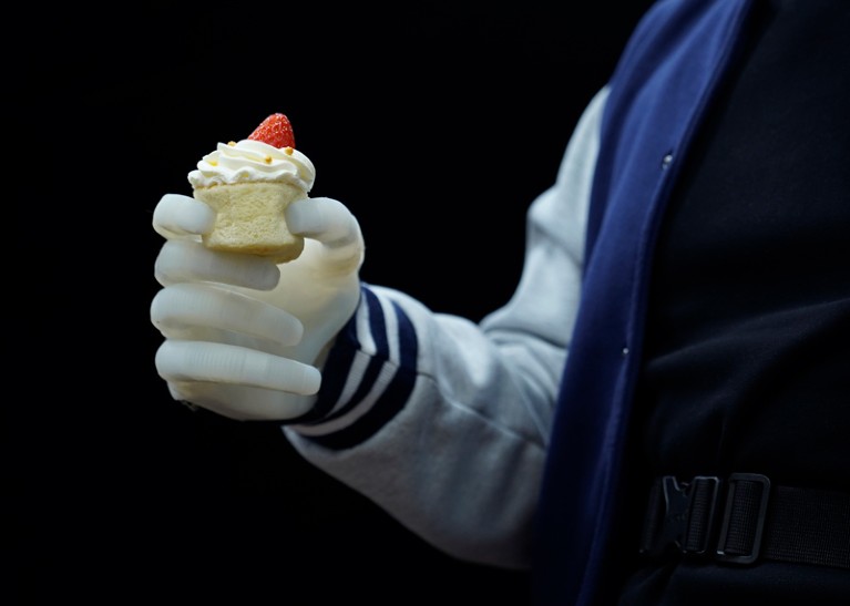 An individual with a transradial amputation wearing the soft neuroprosthetic hand holds a cupcake