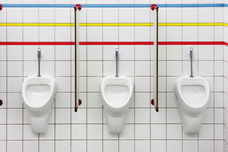 three urinals in a row against a tiled wall