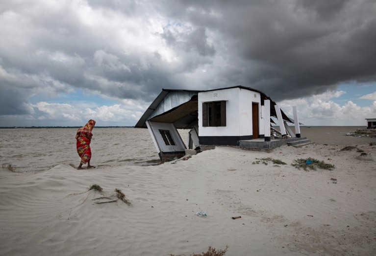 A woman walks to her eroded shelter home near Meghna river in Bangladesh.