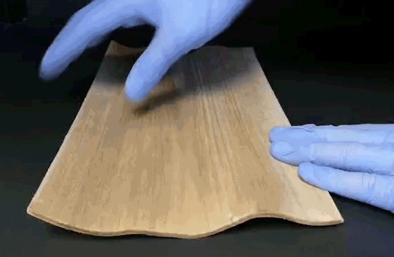 Gloved hands folding wood in half