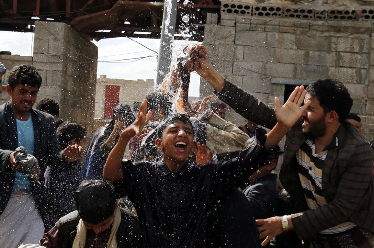 People cool off under a public water drain in Yemen