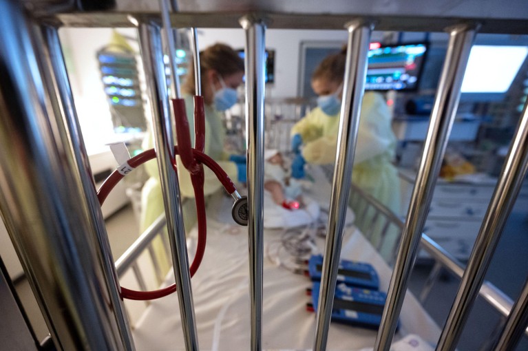 A stethoscope hangs on metal bars of a hospital bed in which a baby with respiratory syncytial virus is being treated by nurses