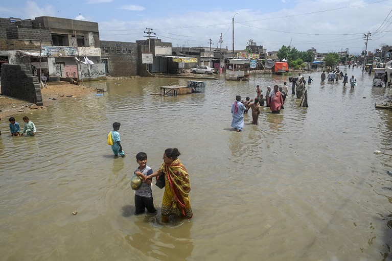 People wade through a flooded street after heavy rains triggered floods in Karachi.