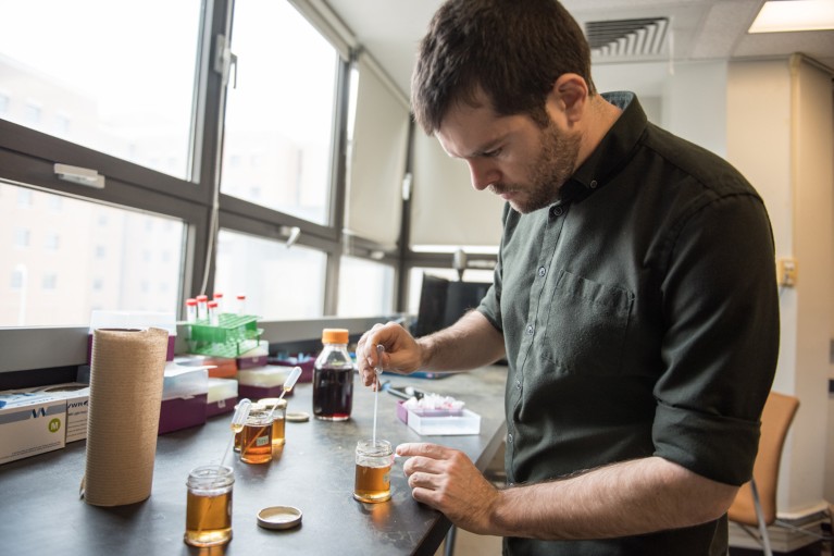 Simon Forest uses a pipette to add drops of maple syrup to a suspension of gold nanoparticles in a test tube to test its purity